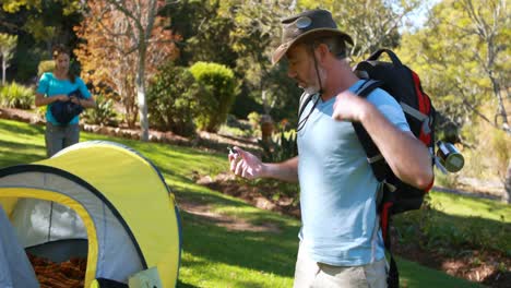 Hiker-with-rucksack-looking-at-compass-at-countryside