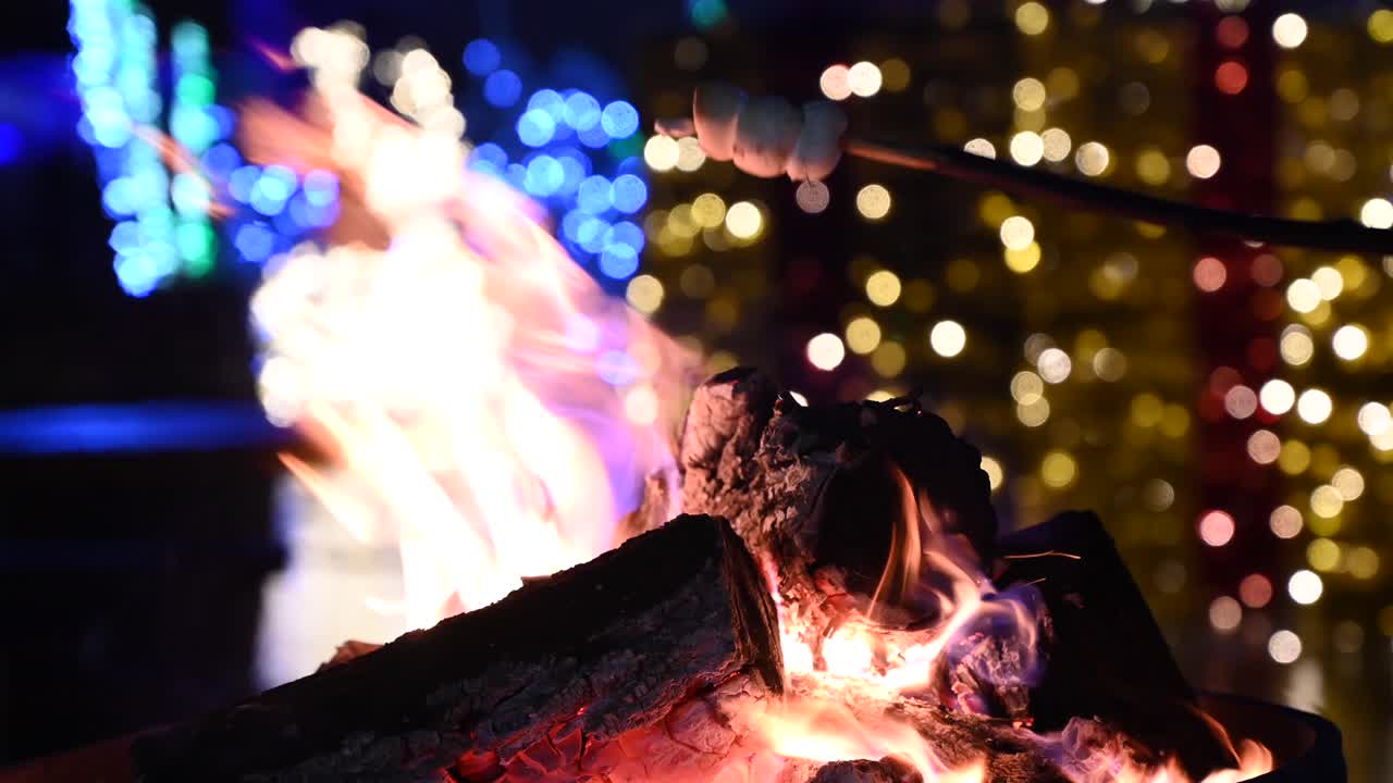 Close up of marshmallows warming up on a burning fireplace with Christmas decor on the background