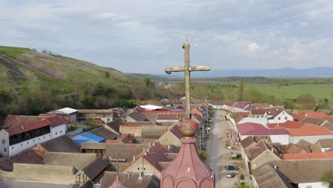 beautiful shot of a cross on a large church in the middle of a small village