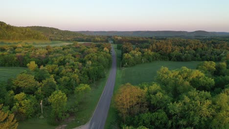 rural road through fields and forest at sunrise/sunset