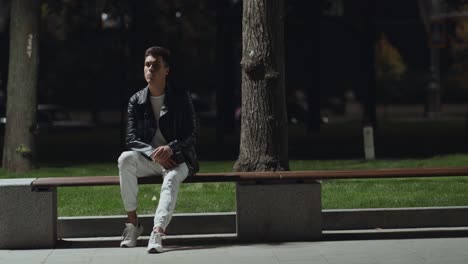 young man sitting on a bench at night