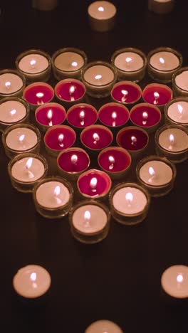 Vertical-Video-Of-Romantic-Red-And-White-Candles-In-the-Shape-Of-A-Heart-On-Black-Background-1