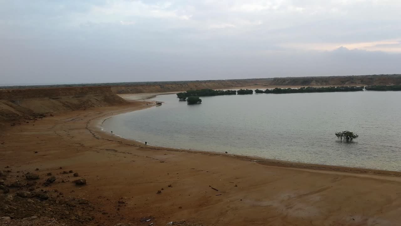 dunas de arena dorada que rodean el tranquilo lago al atardecer en la península de la guajira, colombia - toma amplia