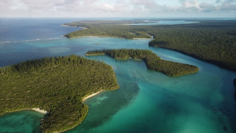 slow flyover above small, forested sunlit islands in oro bay, isle of pines