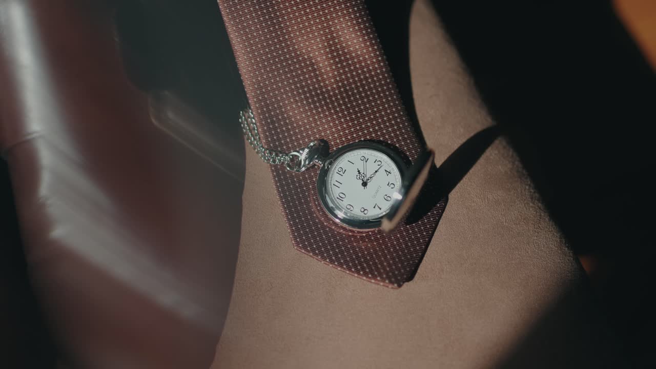 Primer plano de un reloj de bolsillo clásico colocado sobre un traje con detalle de corbata