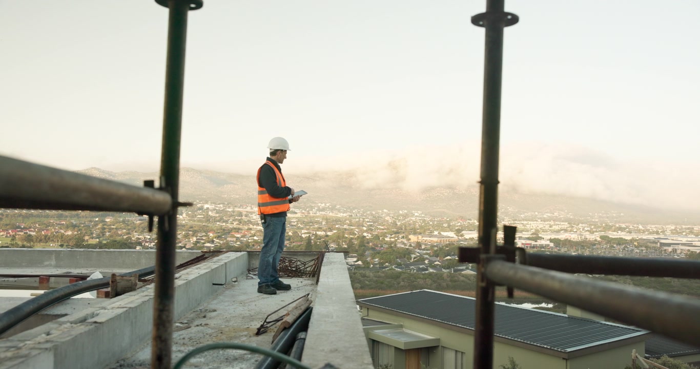 Ingeniero de construcción inspeccionando el sitio de obra desde la azotea