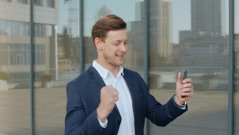 surprised businessman receiving good news on smartphone at street