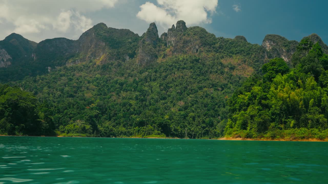 Góc nhìn thứ nhất từ thuyền đi qua hồ Khao Sok màu ngọc lam ngoạn mục với những ngọn núi đá vôi cao chót vót và thảm thực vật nhiệt đới tươi tốt