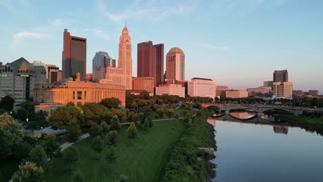 Ascenso-Aéreo-De-La-Hora-Dorada-Al-Horizonte-De-La-Ciudad-Desde-Los-árboles---Columbus,-Ohio