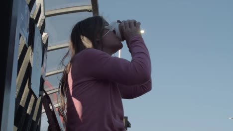 mujer con máscara tomando café plano medio