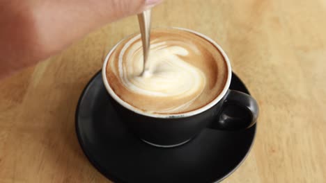 Person-hand-stirring-coffee-with-spoon