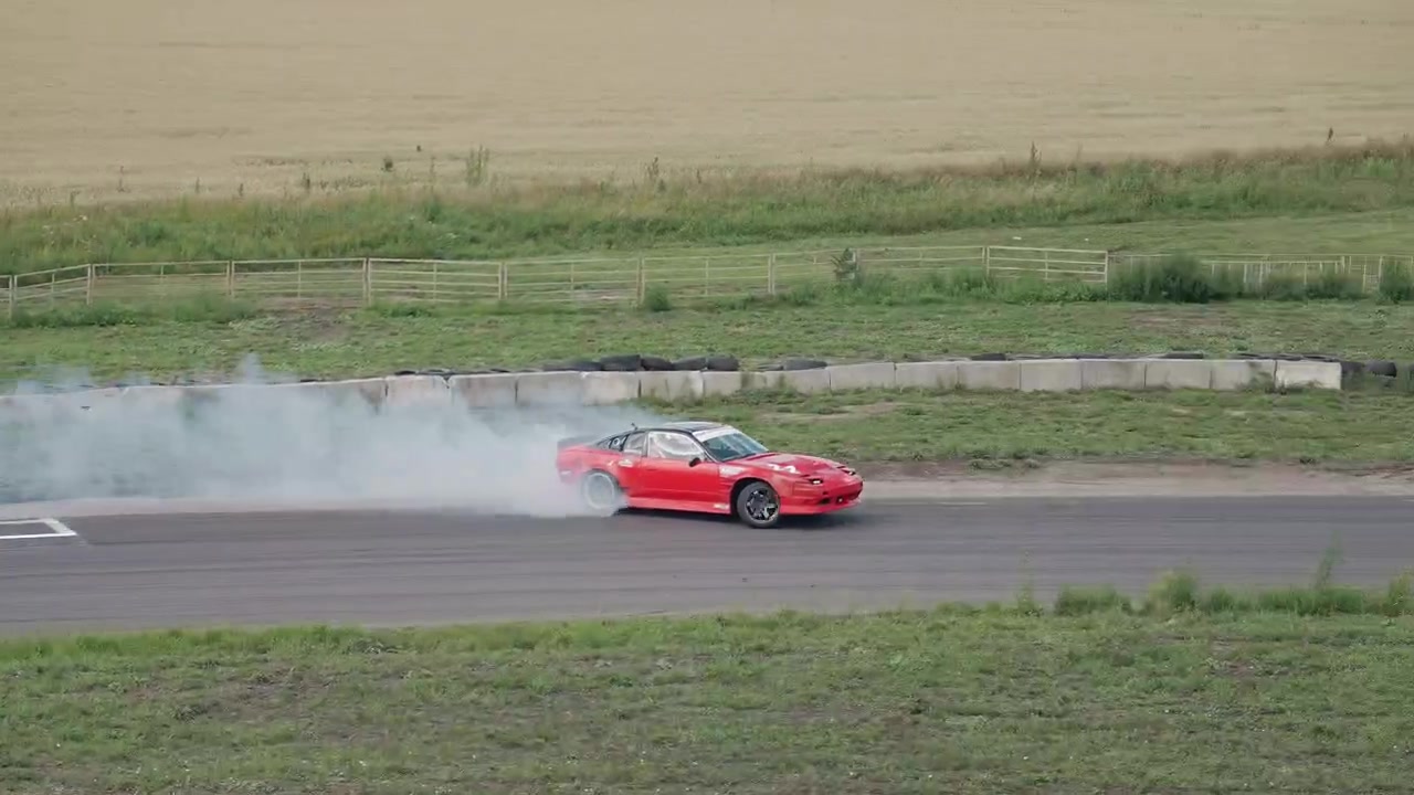 Rød sportsvogn drifter på racerbane med dækrøg