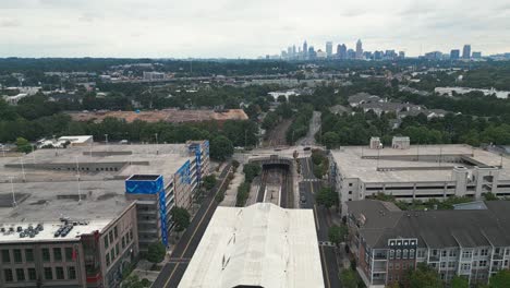 aerial approaching shot of lindbergh marta station and skyline of atlanta city in background during cloudy day