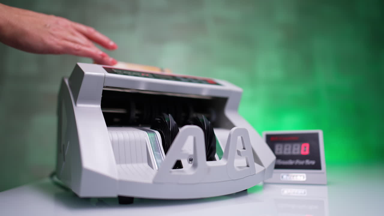 Hand places fifty euro bills into the cash counting machine. Bank equipment calculates banknotes quickly. Close up. Blurred backdrop.