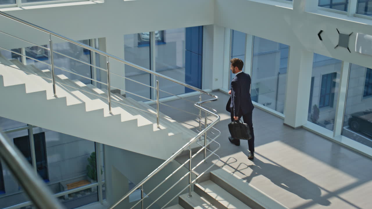 Entrepreneur walking stairs modern building holding briefcase. Confident ceo man