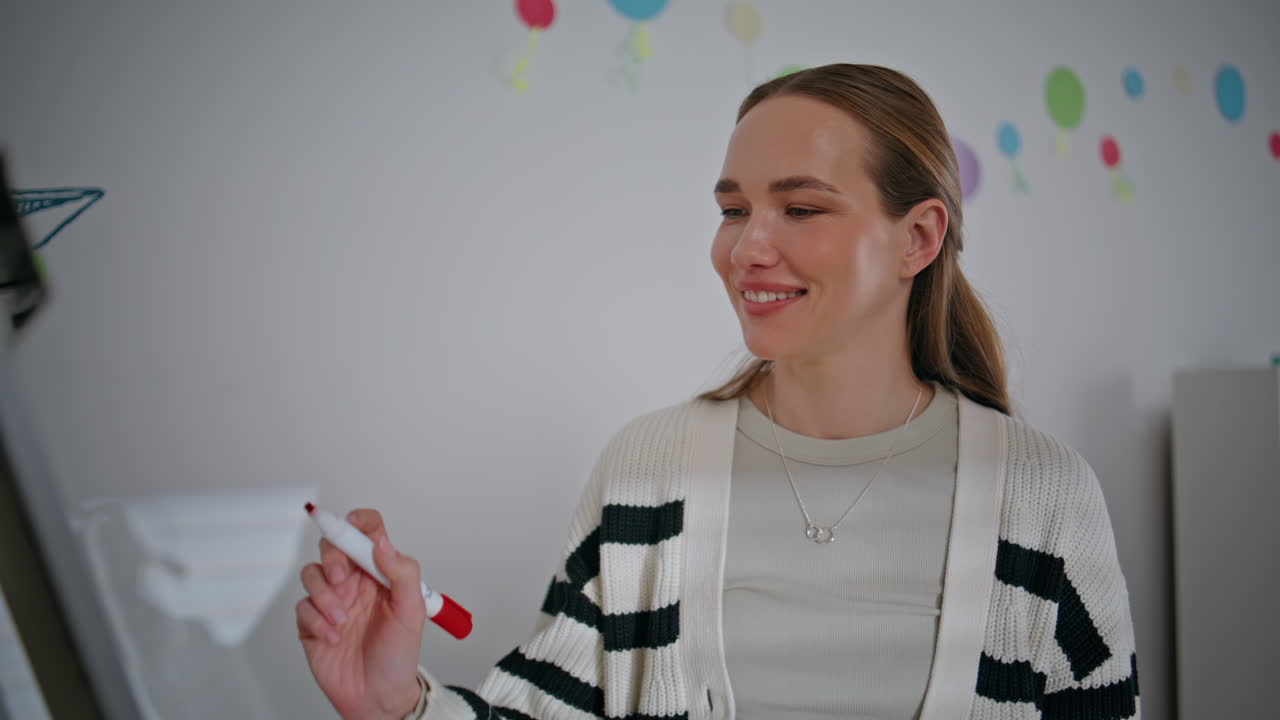 Woman educator beginning lesson talking near whiteboard in classroom closeup