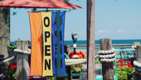 inscription open on a rotating weather vane against the background of the sea and summer cafes trave