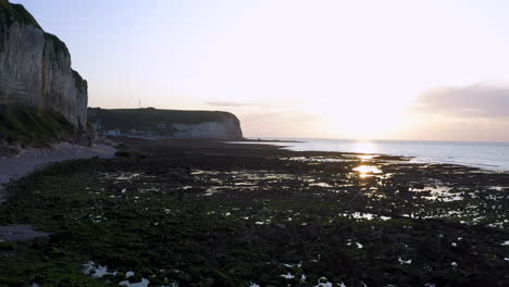 Low-altitude-flight-over-low-tide-atlantic-beach-at-sunset