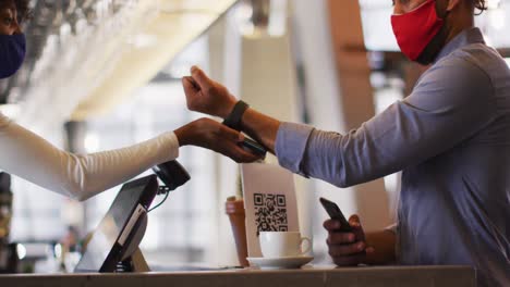 Mixed-race-man-giving-african-american-female-cafe-worker-his-smartwatch-in-order-to-pay