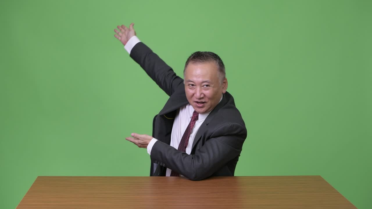 성숙한 일본인 사업가가 무언가를 보여주고 있습니다.