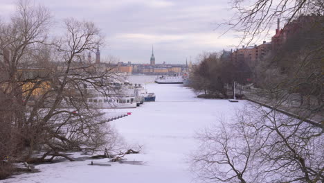 frozen palsundet with moored boats, gamla stan skyline in distance