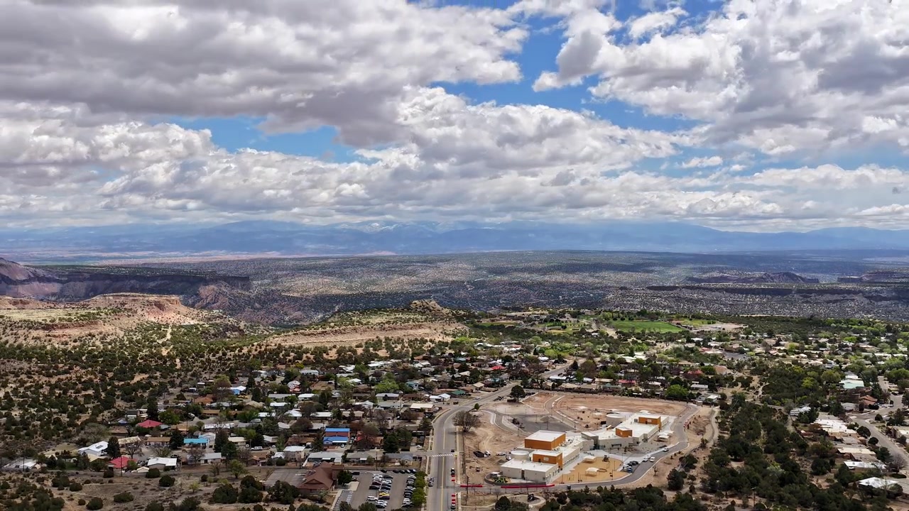 4K drone-timelapse fanger skyformationer og skiftende lys over en forstad beliggende oven på en kløft. Filmisk bevægelse afslører skygger, der bevæger sig hen over beboelsesgader og et stort landskab.