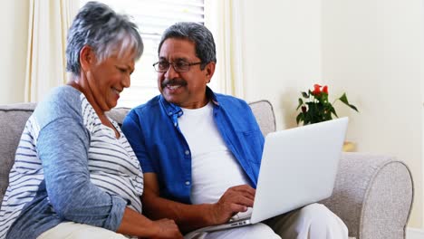 Senior-couple-using-laptop-in-living-room-4k