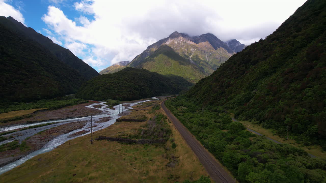 Aerial tracking shot flying over a road at the Otira River, in New Zealand