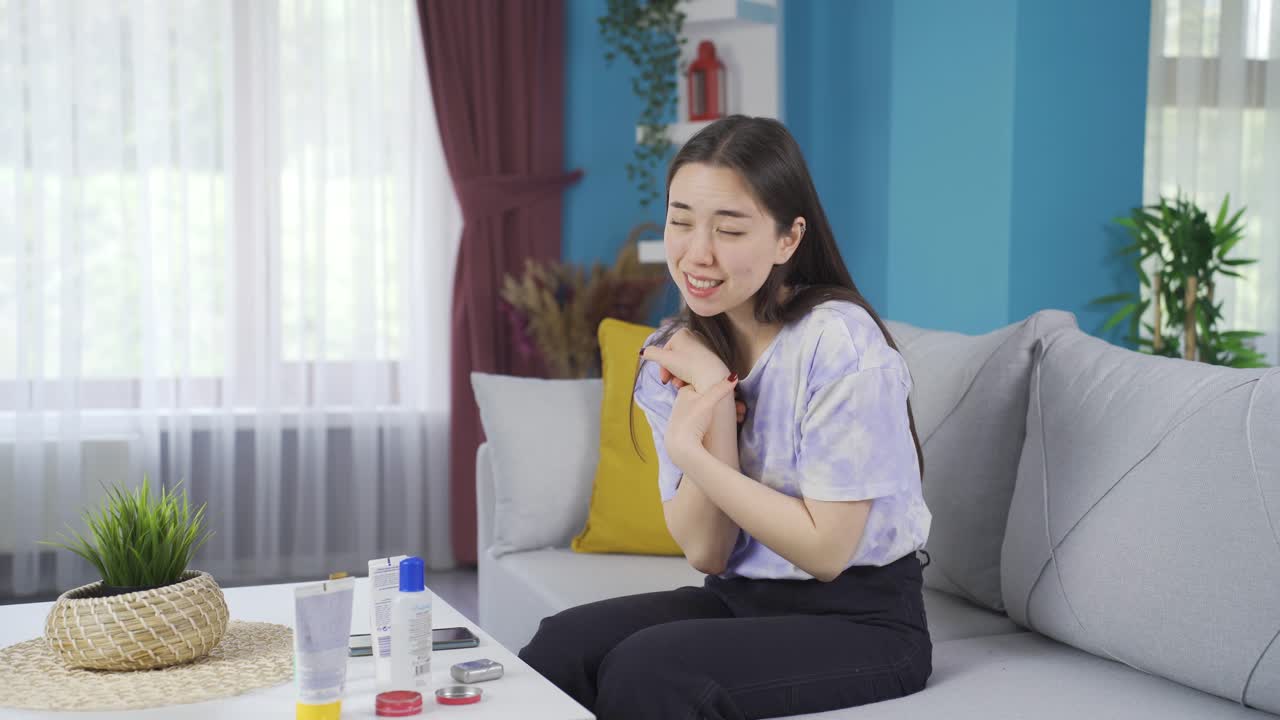 어린 아시아 소녀가 통증이 있는 관절과  ⁇  부위에 크림을 바르고 있습니다.