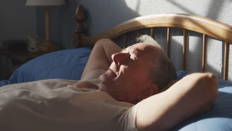 senior man lying on bed at home