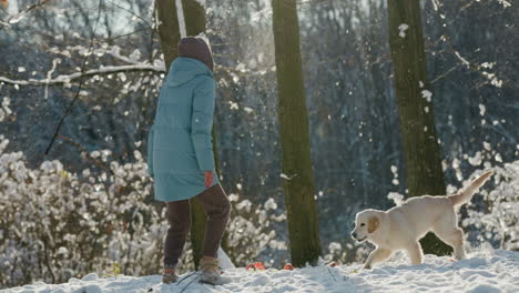 happy woman running in the snow with her dog, having a good time on a walk in the winter forest