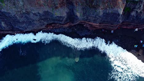 bird's eye shot of waves fading smoothly on rocky beach, tenerife, spain