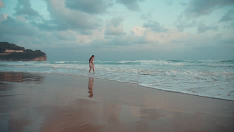 Happy-girl-enjoying-morning-at-seaside.-Young-woman-looking-on-waves-at-sea-surf