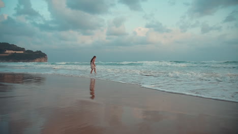 happy girl enjoying morning at seaside. young woman looking on waves at sea surf