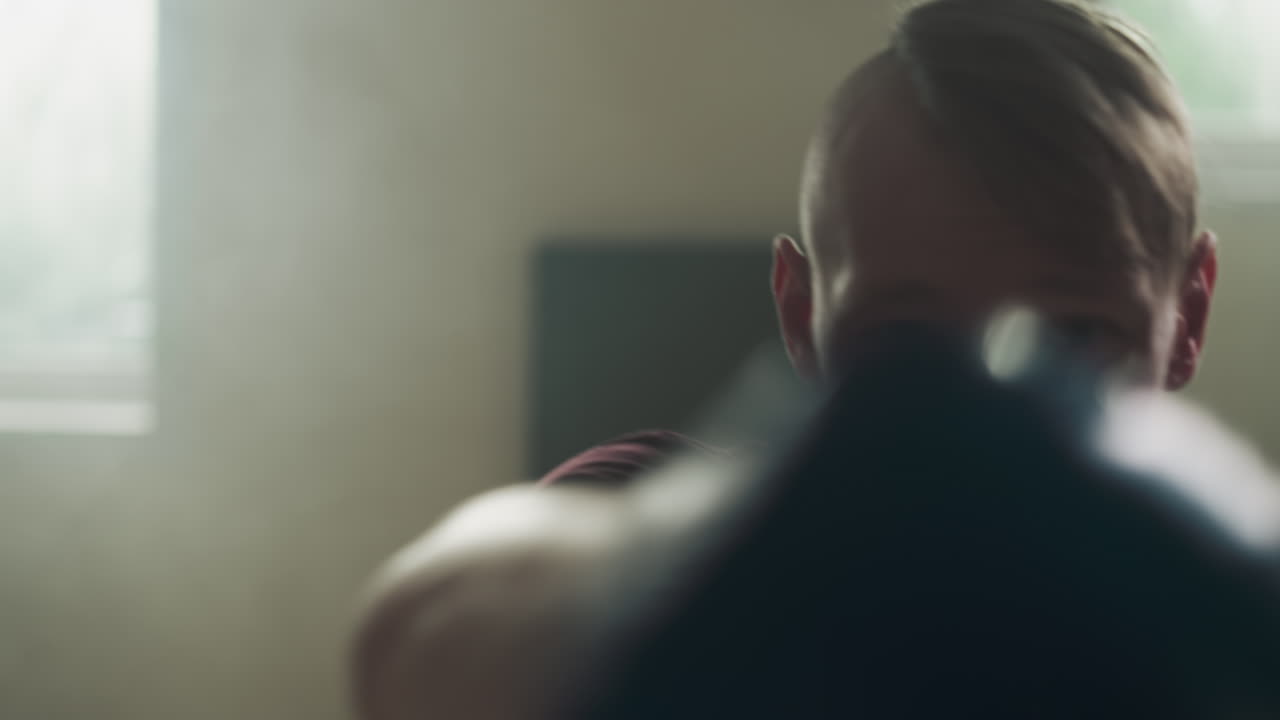 스포츠 센터에서 주먹으로 치 훈련을 하는 운동 선수. 집중된 운동 선수는 체육관에서 느린 동작으로 전투 기법을 수행합니다. 격렬한 전투 운동.