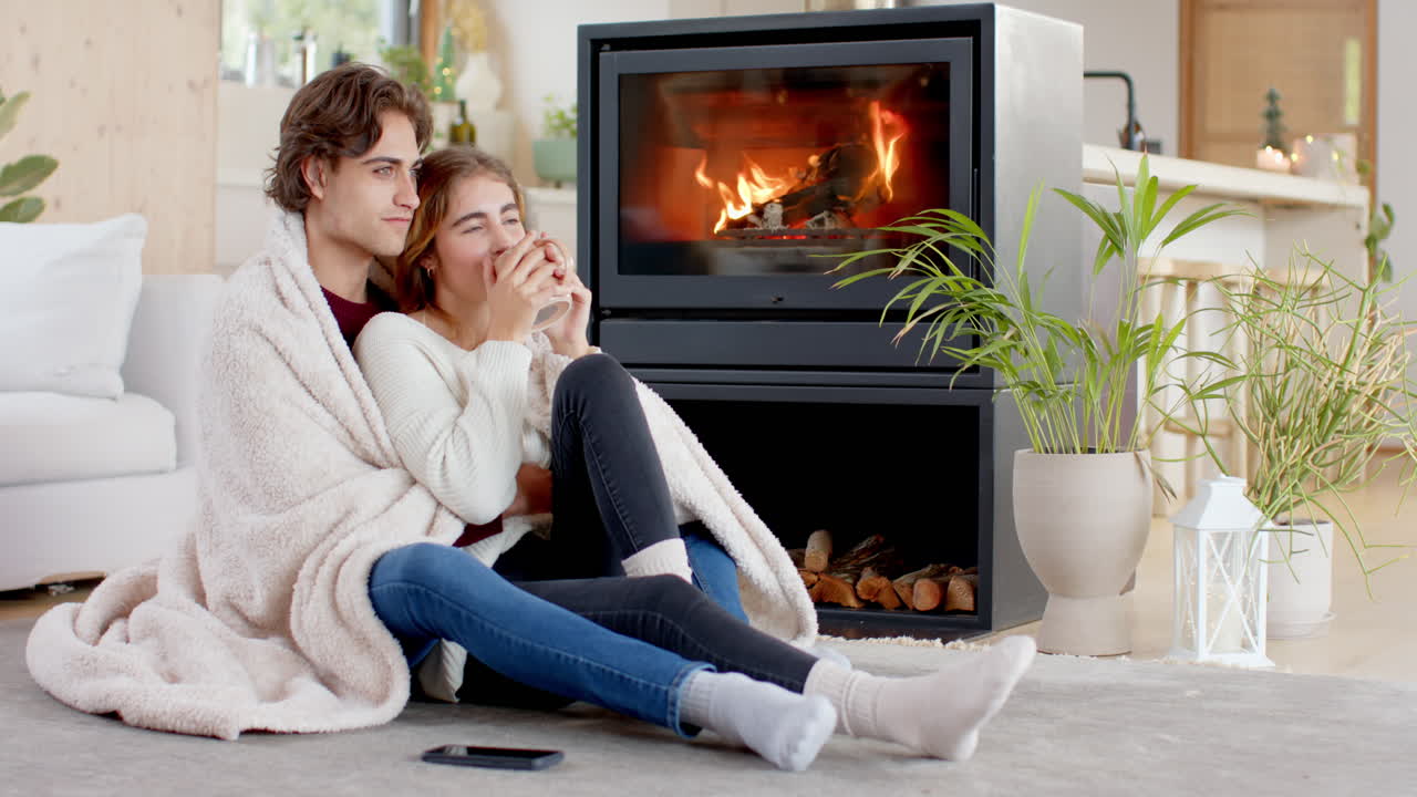 Christmas time, Couple cuddling by cozy fireplace, wrapped in blanket, enjoying warm holiday moments