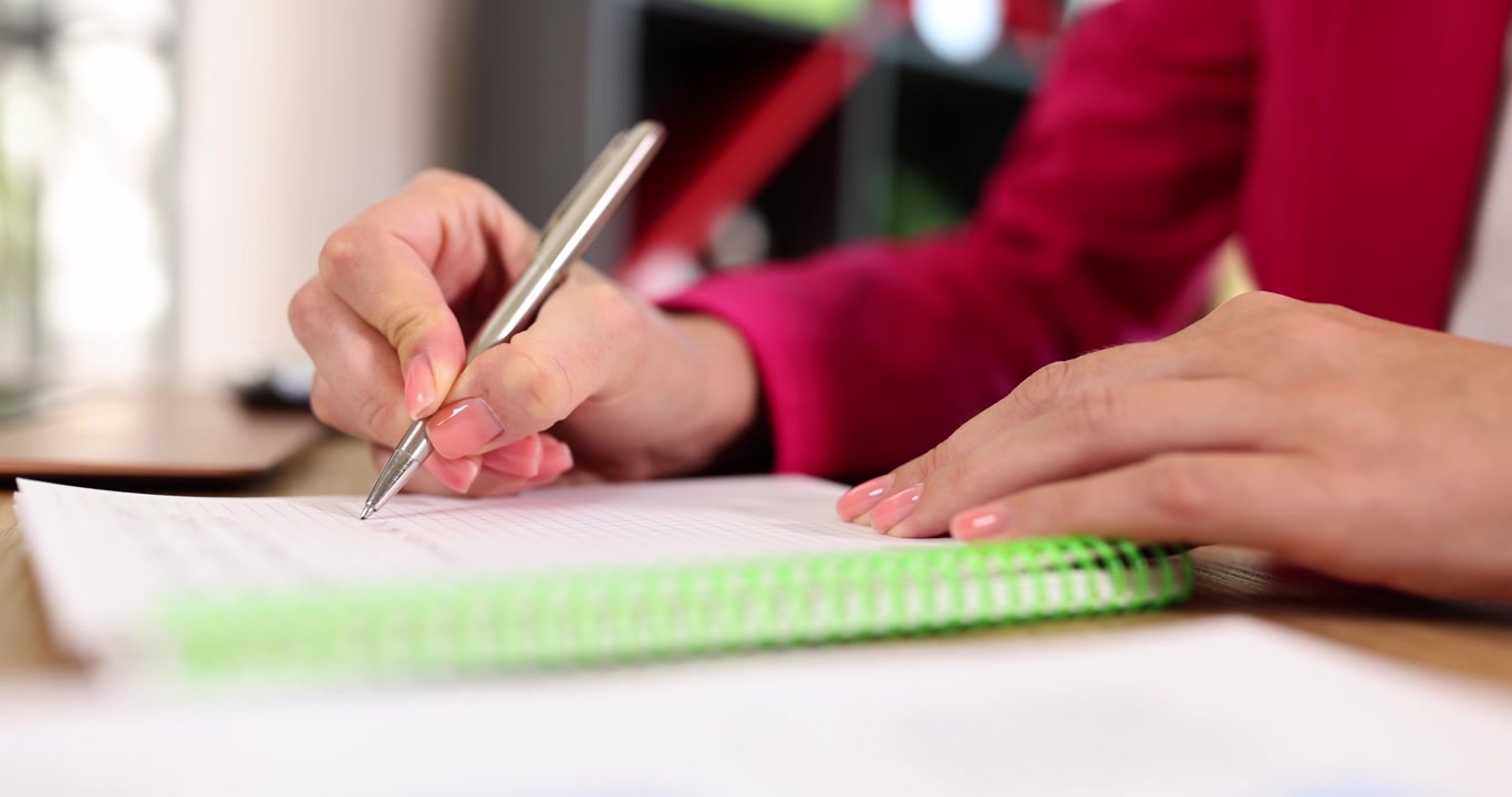 Female hands write with a pen in a notebook closeup