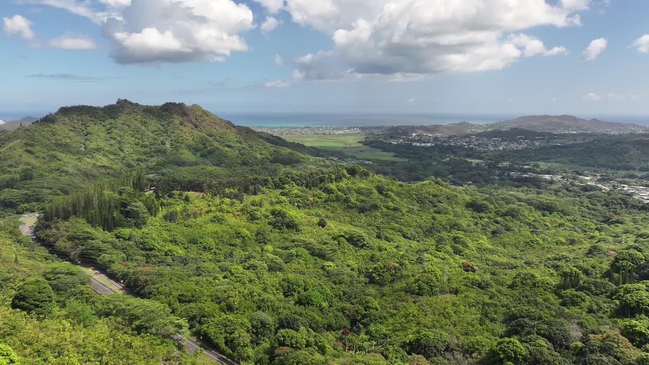 Aerial drone footage over Hawaii’s lush green mountains and tropical coastline, showcasing turquoise ocean waters, palm trees, scenic valleys, and vibrant island landscapes from above