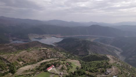 Front-drone-video-in-"golden-hour"-advancing-over-the-mountains-of-SH22-in-albania,-over-the-village-of-Va-Spas-and-in-the-background-Lake-Drin