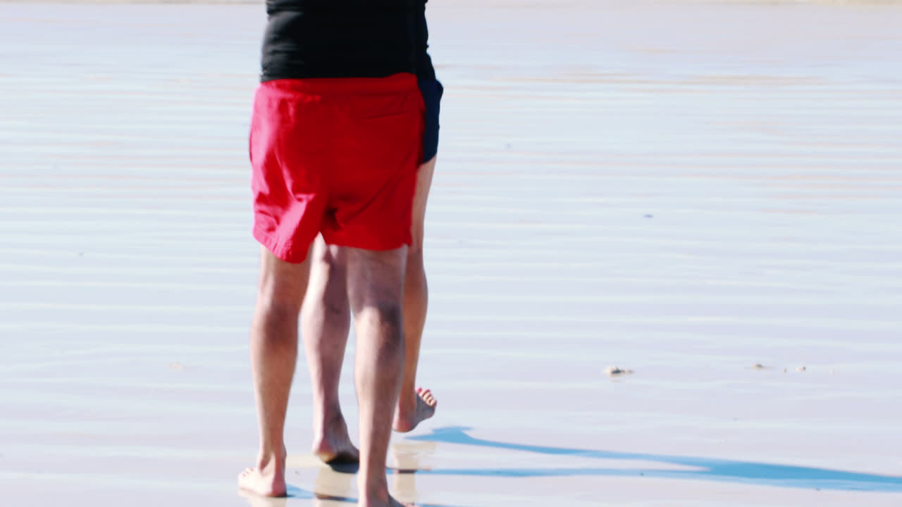 고령 부부는 바다를 향해 는 동안 머리 위에 서프보드를 들고 있습니다.