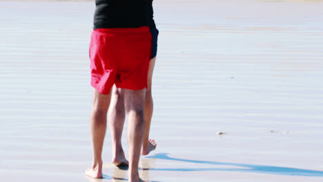 senior couple carrying surfboard over head while walking towards the sea