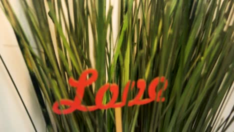 red wooden sign that says "love" in a plant