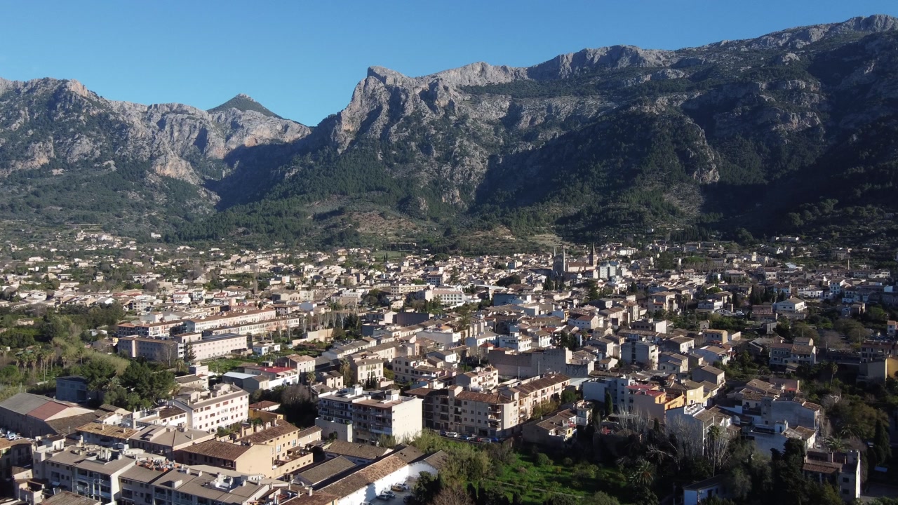 Aerial approach to the town of Sóller with the Tramuntana mountain range in the background. Mallorca, Spain.