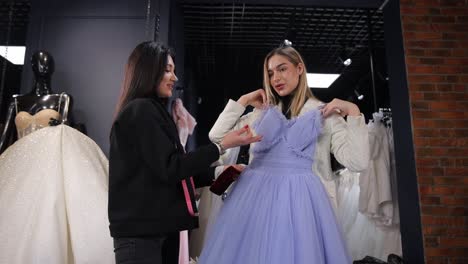 Sales Consultant Helping Young Woman Choose Elegant Evening Dress in Fashion Salon . Sales consultant helping young woman choose elegant evening dress in fashion salon
