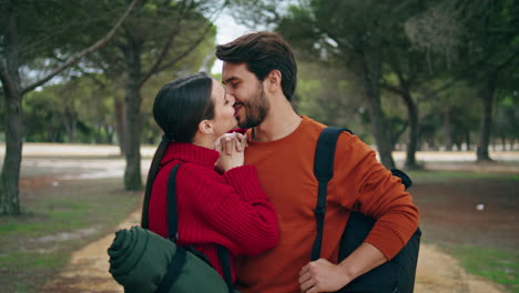 lovely couple standing forest path vertical close up. woman kissing bearded man