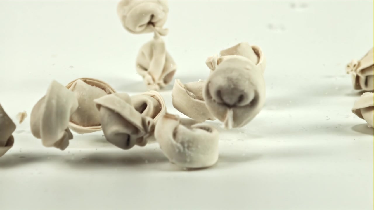 Raw Dumplings Falling onto a White Surface in Slow Motion