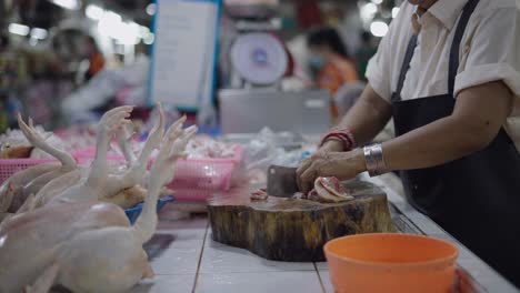 woman cutting fresh chicken at a market