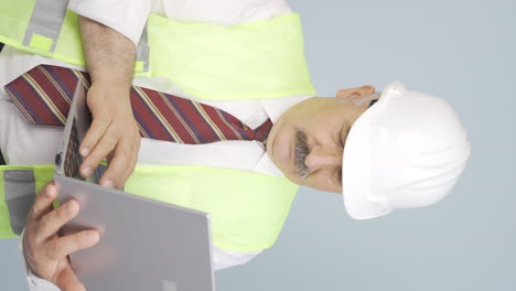 video vertical de un viejo ingeniero sosteniendo una computadora portátil riéndose de la cámara.