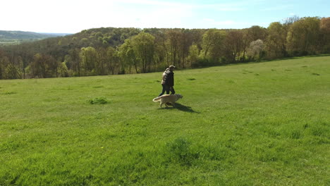 Toma-Aérea-De-La-Pareja-Madura-Y-El-Perro-A-Caminar-En-El-Campo