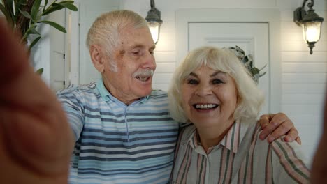 senior elderly caucasian couple using mobile phone for video call, making selfie in porch at home